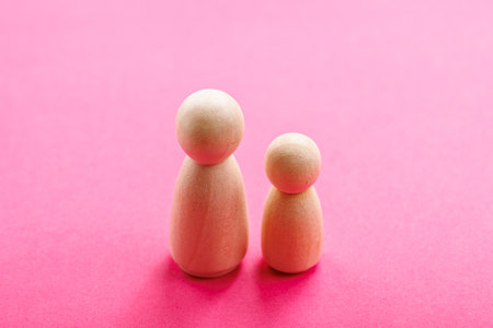 Two wooden figures on vibrant pink background.