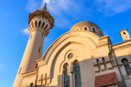 Architectural beauty of historic mosque with minaret against blue sky.の写真素材