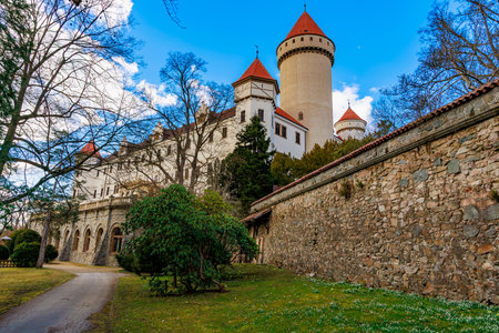 Medieval castle with red towers amidst lush greenery and stone walls.の写真素材