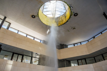 Fountain inside modern building atrium with skylight and water features.
