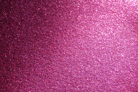 A pink background with a lot of glitter. The glitter is scattered all over the backgroundの写真素材