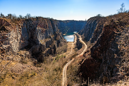 Scenic canyon with rugged cliffs and serene lake under clear blue sky.