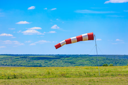 Red and white windsock on a sunny day in green pasture.の写真素材
