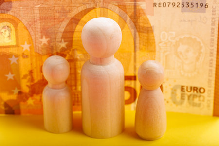 Wooden figures against euro banknote background symbolizing financial concepts.