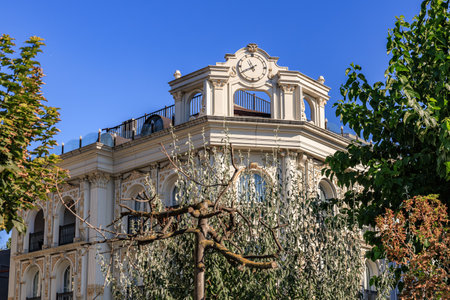 Elegant architectural building with clock tower and ornate facade under blue sky.
