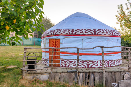A blue and red tent with a red stripe on the side. The tent is in a field with trees in the background.の写真素材