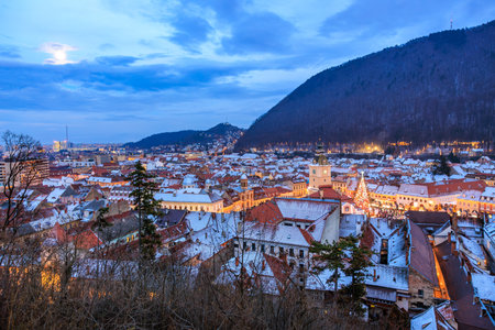 A city at night with a full moon in the sky. The city is lit up with lights and the buildings are...