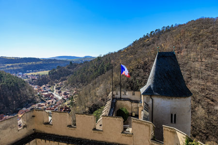 Karlstejn castle with czech flag overlooking scenic vltava river valley.の写真素材