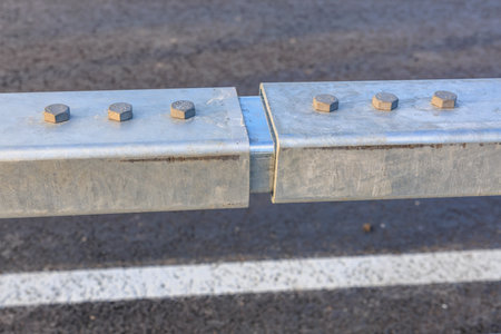Close-up of metal guardrail junction with bolts on road.の写真素材