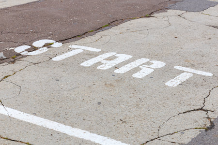 Weathered start line on cracked asphalt road surface.