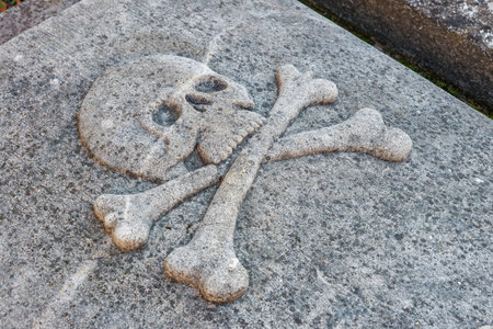 Skull and crossbones stone carving on weathered surface.