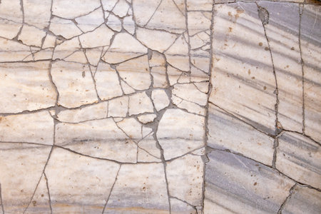 Cracked marble surface with light gray and tan veining patterns.