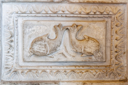 Ancient stone carving of fish in relief with geometric patterns.の写真素材