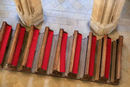 Aerial view of empty wooden church pews with red cushions in stone interior.の写真素材