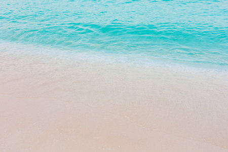 The ocean is calm and the water is a beautiful shade of blue. The sand is white and the waves are gentleの写真素材