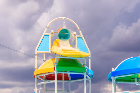 A colorful slide with a blue and green top and a yellow bottom. The slide is in the middle of a...