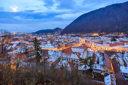 A city at night with a large building in the background. The sky is cloudy and the city is lit upの写真素材