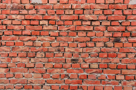 Red brick wall with weathered surface in urban setting.