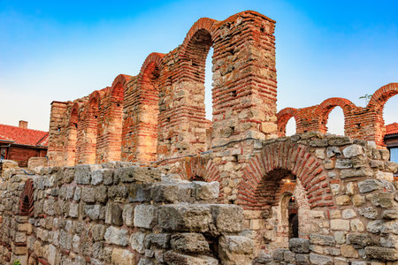 Ancient red brick ruins against blue sky featuring arched doorways in historical setting.の写真素材
