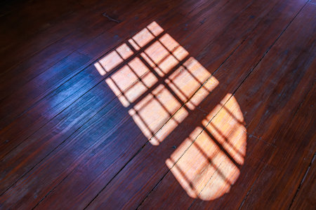 Sunlight casting window pattern on wooden floor.の写真素材