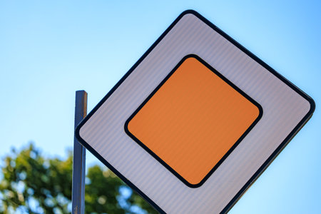 Priority road traffic sign with blue sky and greenery background.の写真素材