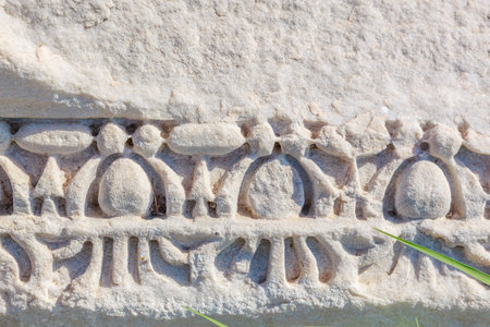 Ancient stone relief with geometric patterns and natural weathering detail. Authentic ancient Smyrna ruins in Izmir, Turkey.の写真素材