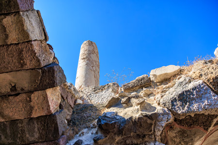 Ancient stone ruins under clear blue sky with central column view. Authentic ancient Smyrna ruins in Izmir, Turkey.の写真素材