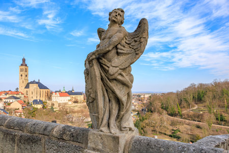 Historic angel statue overlooking european cityscape with church and blue sky.. March 22, 2025, Kutna Hora, Czech Republic.のeditorial素材