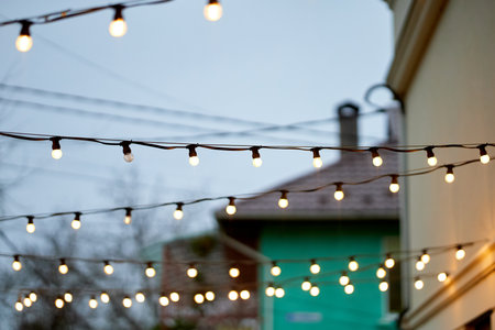 String of lights is hanging from the roof of a building. The lights are lit up and create a warm,...