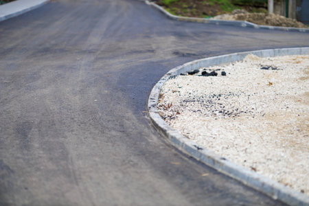 Freshly paved road with gravel shoulder on a curved path.の写真素材