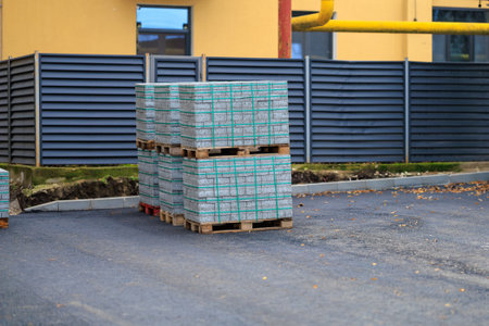 Pallets of concrete blocks or paving slabs at construction site on asphalt surface.の写真素材