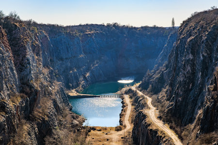 Scenic quarry with turquoise water and rocky cliffs under clear sky.の写真素材