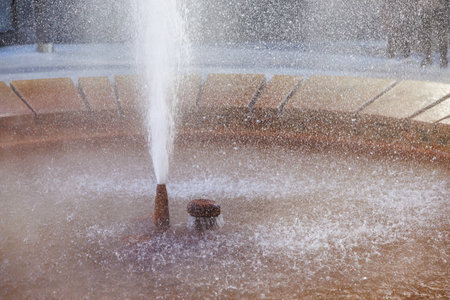 Refreshing fountain with splashing water in sunlit urban setting.の写真素材