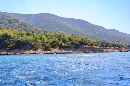 Serene coastal landscape with lush green hills and sparkling blue sea.の写真素材