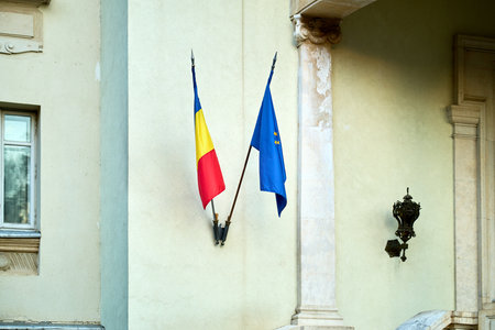 Romanian and european flags on building exterior wall.