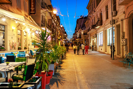 Evening stroll in charming european street with outdoor cafes and lights. May 3, 2025 Constanta Romania.のeditorial素材