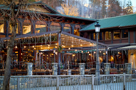 Cozy wooden winter cafe with festive lights on a quiet evening. December 13, 2025 Sinaia Romania.のeditorial素材