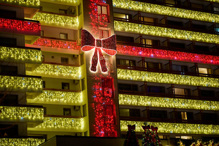 Festive christmas lights on city building exterior with large illuminated bow. December 13, 2025 Sinaia Romania.のeditorial素材