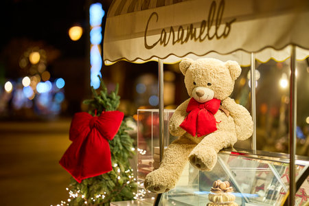 Festive teddy bear display with red bow at nighttime christmas market. December 13, 2025 Sinaia Romania.のeditorial素材
