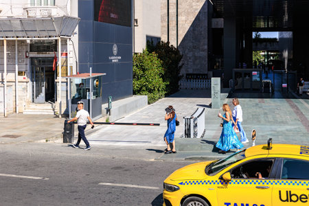 Urban scene with caucasian adults in blue dresses and taxi on sunny day. August 12, 2025 Istanbul Turkey.のeditorial素材