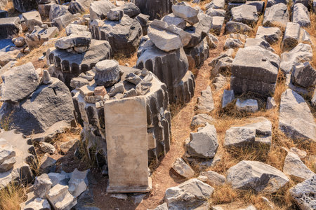 Ancient stone ruins with weathered basalt columns and grass. August 8, 2025, 2 Didim Turkey.のeditorial素材