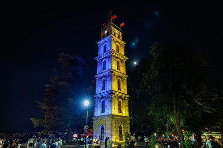 Historic Bursa clock tower illuminated at night with visitors nearby. August 9, 2025, 2 Bursa Turkey.のeditorial素材