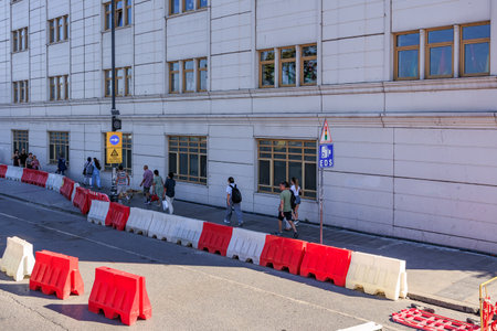 Urban street scene with diverse people walking along sidewalk near barrier. August 12, 2025 Istanbul Turkey.のeditorial素材