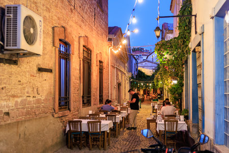 Charming outdoor dining in cozy mediterranean alley at dusk. August 3, 2025, Ayvalik, Turkey.のeditorial素材