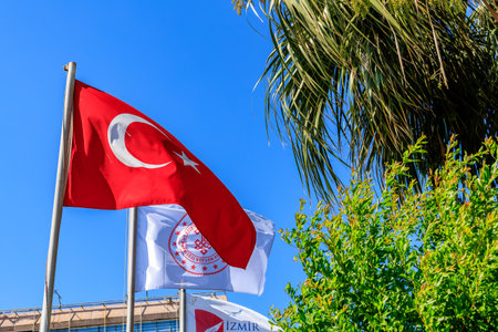 Turkish national flag and izmir emblem banners against clear blue sky. August 4, 2025, Izmir Turkey.のeditorial素材