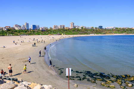 Sunny beach day at lush urban park with clear waters and people relaxing. May 3, 2025 Constanta...