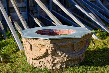 Ornate stone well with carved designs in sunlit garden. December 13, 2025 Sinaia Romania.のeditorial素材