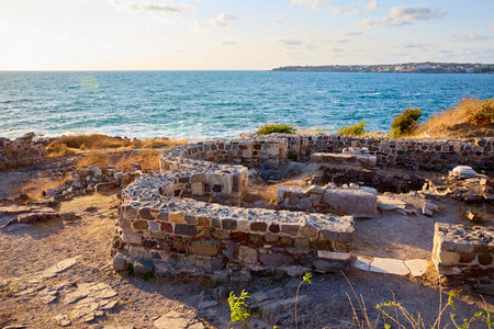 Ancient ruins by the sea during sunset.