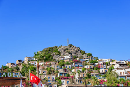 Picturesque turkish coastal village with rocky hill and vibrant architecture. August 5, 2025, Bodrum Turkey.のeditorial素材