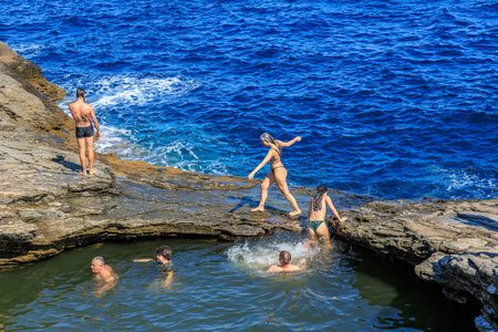 A group of people are playing in the ocean. The water is blue and the people are in the water. August 6, 2024 Giola Thassos Greece.のeditorial素材